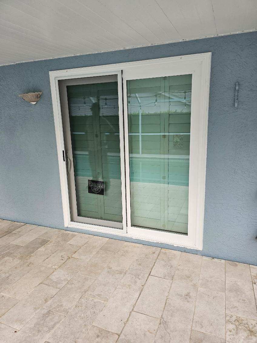 Sliding glass door, white frame, against blue wall, tan tile floor.