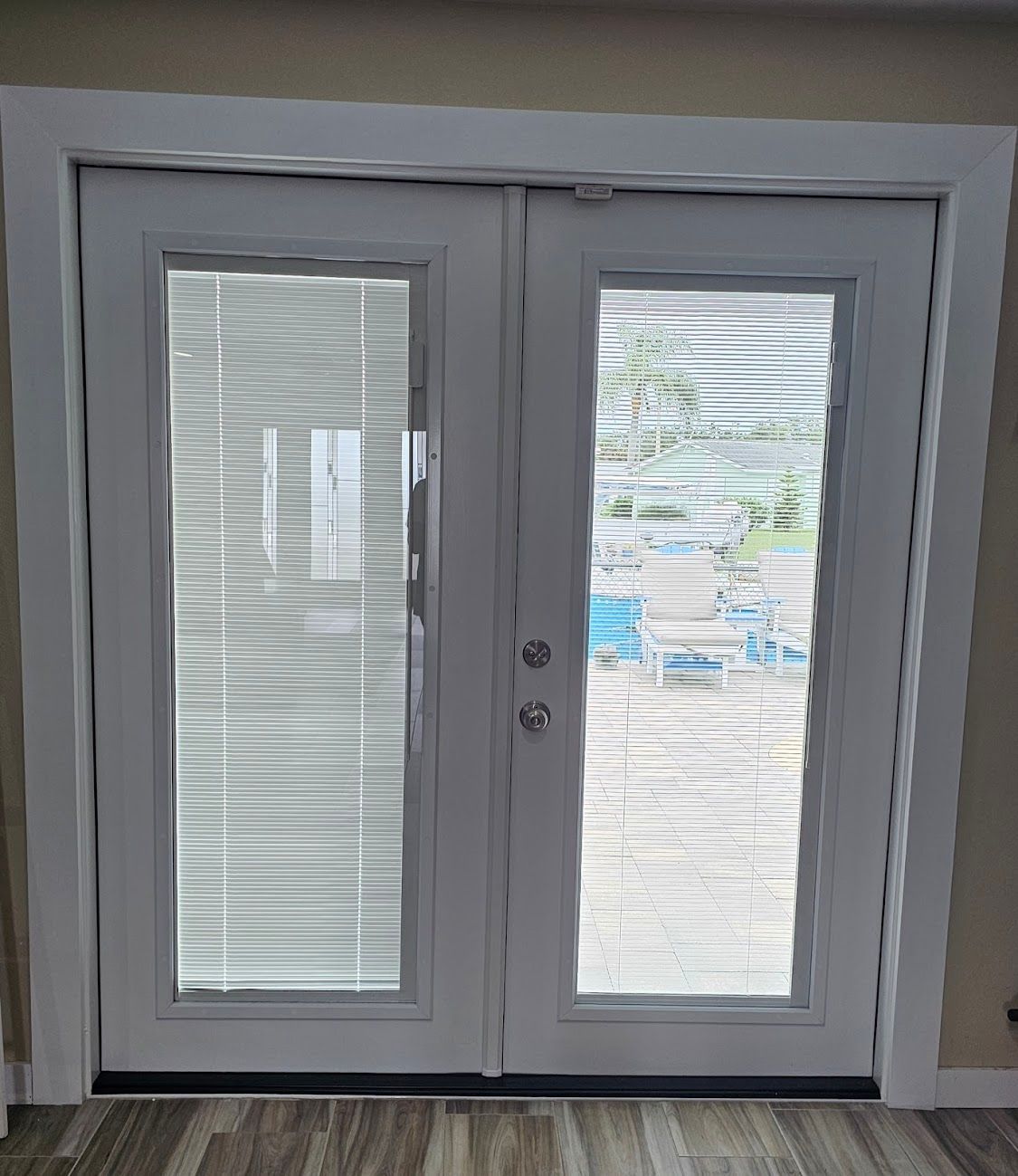 White double doors with glass panels and blinds; exterior view visible.
