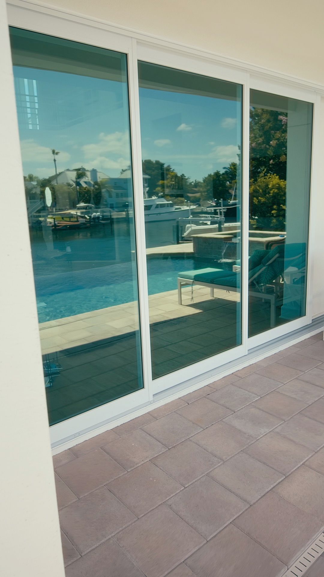 Sliding glass doors reflecting a marina with boats, blue water, and a sunny sky.