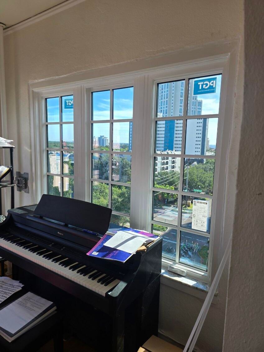 Piano by a window with a city view, sheet music, sunny day.
