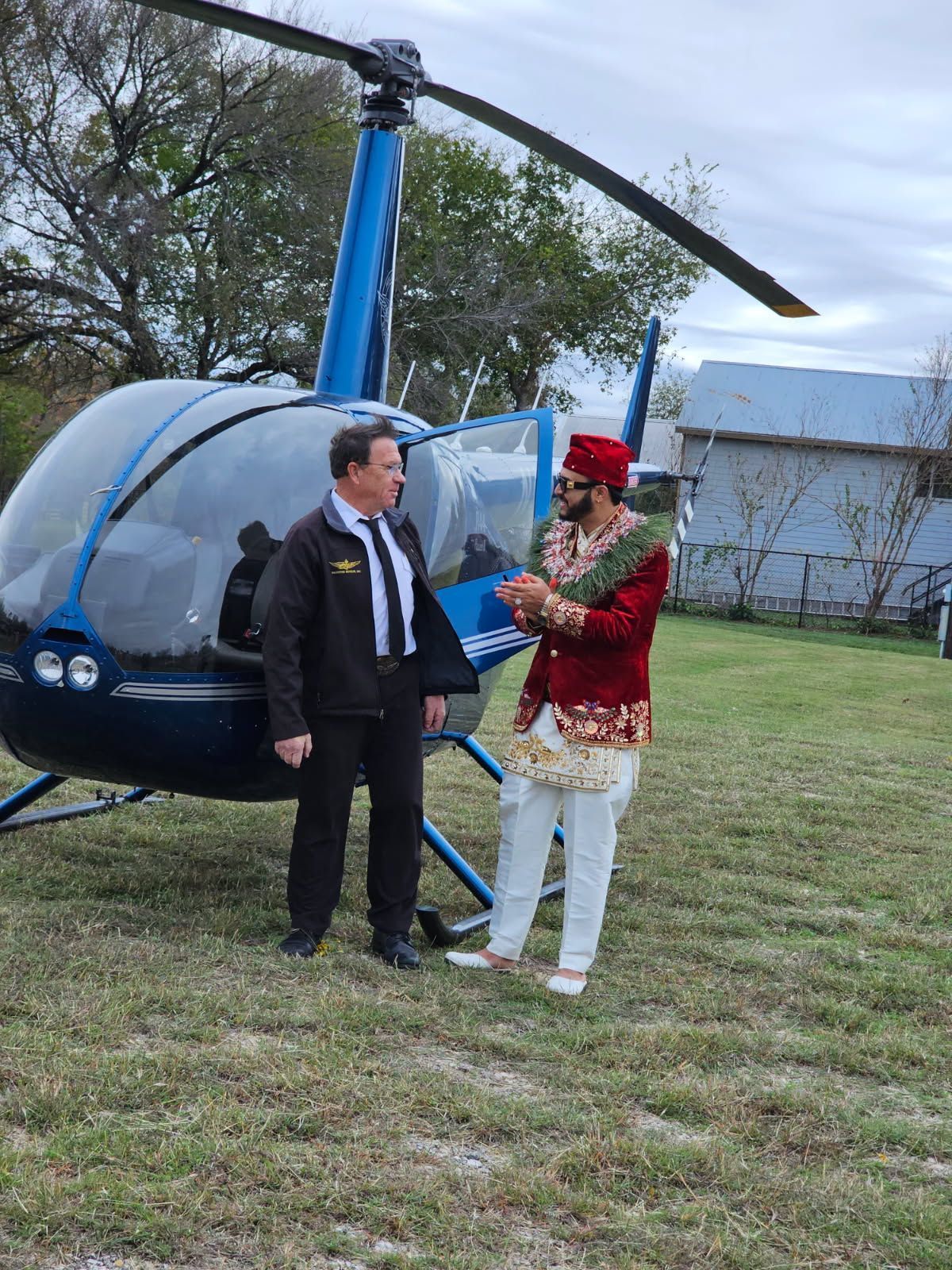 Mike with groom in a traditional attire near a blue helicopter