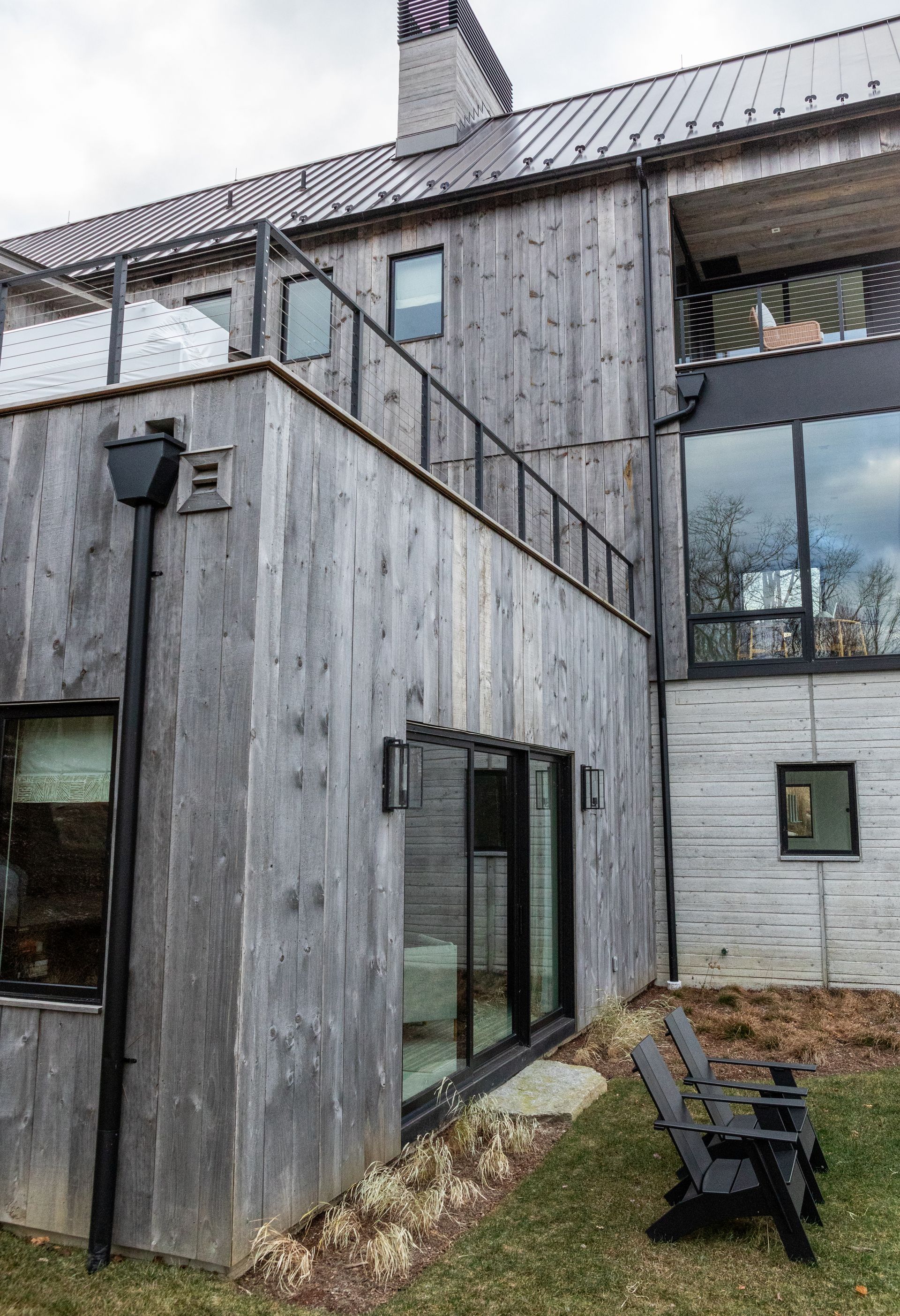 A large wooden house with a lot of windows and chairs in front of it.