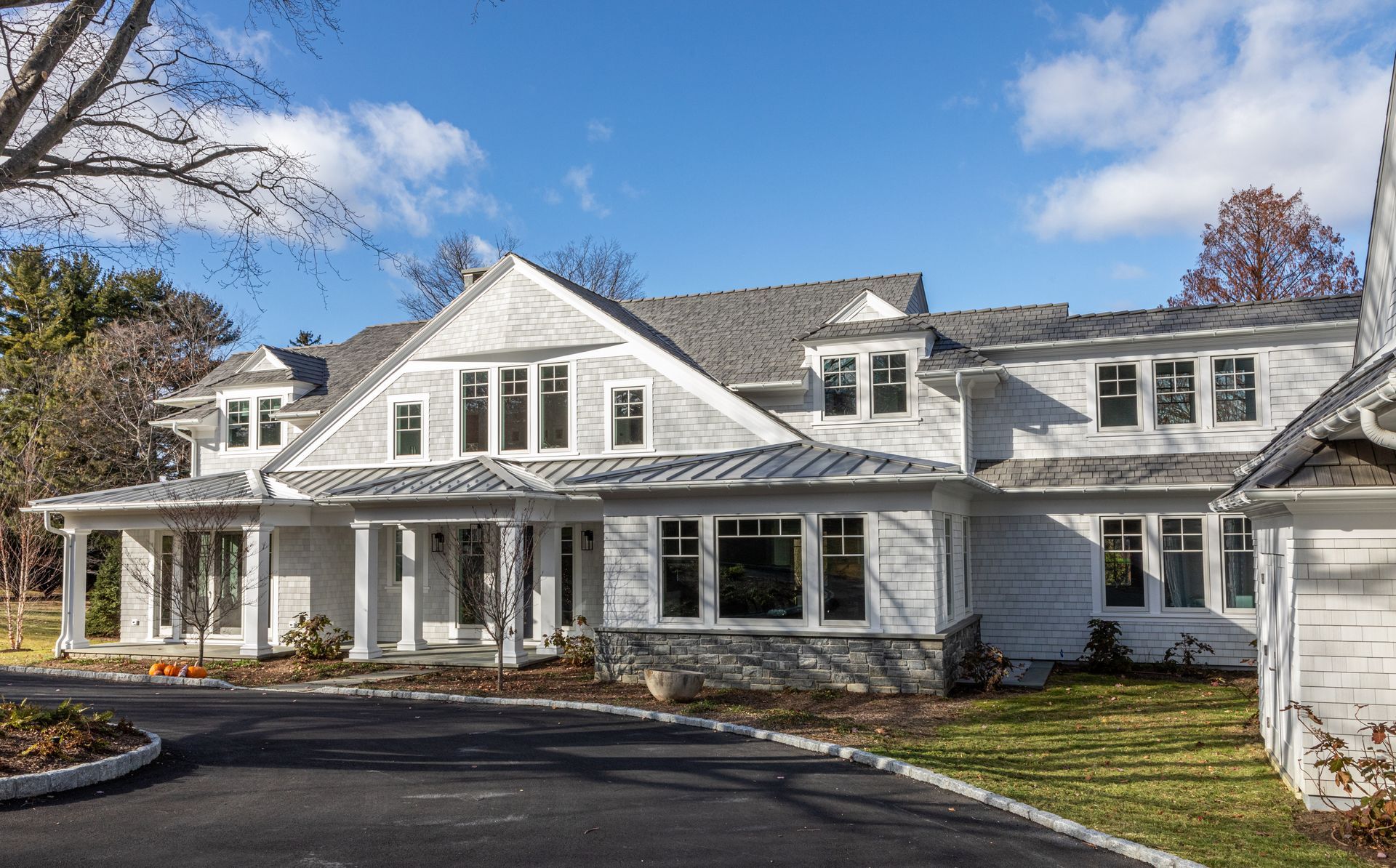 A large white house with a lot of windows is sitting on top of a lush green hillside.