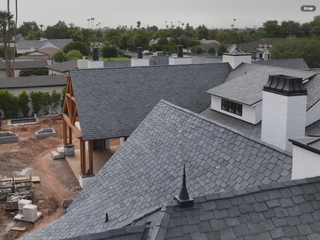 Rooftops of a house under construction with gray shingles and white chimneys, viewed from above