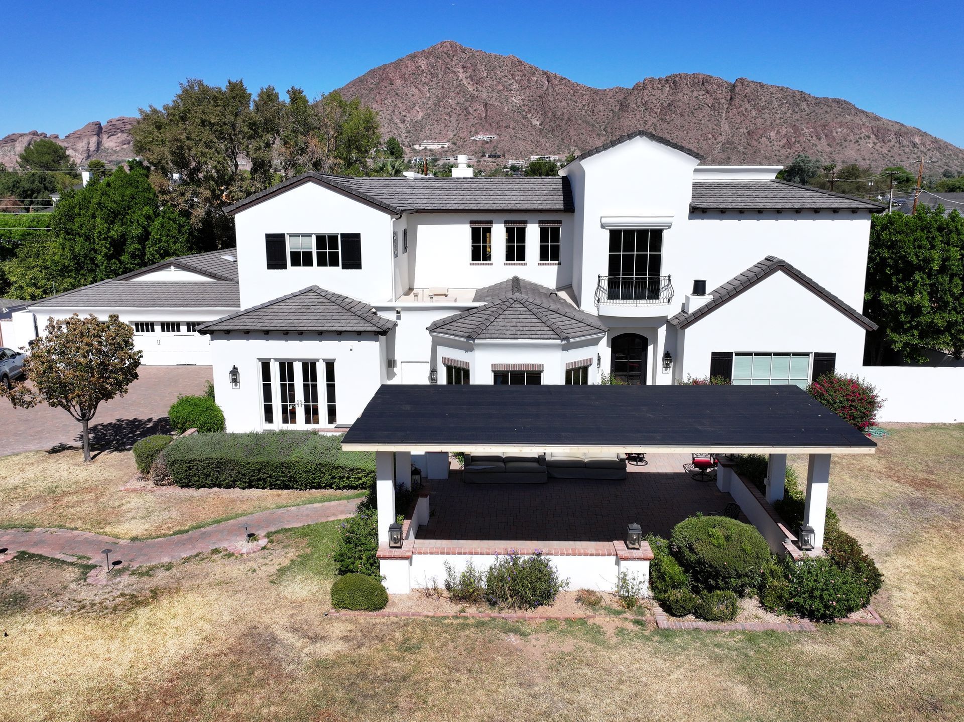 an aerial view of a large white house with mountains in the background