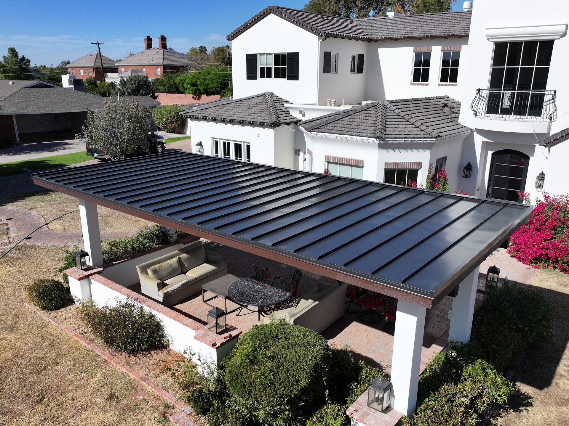 an aerial view of a large white house with a pergola in front of it