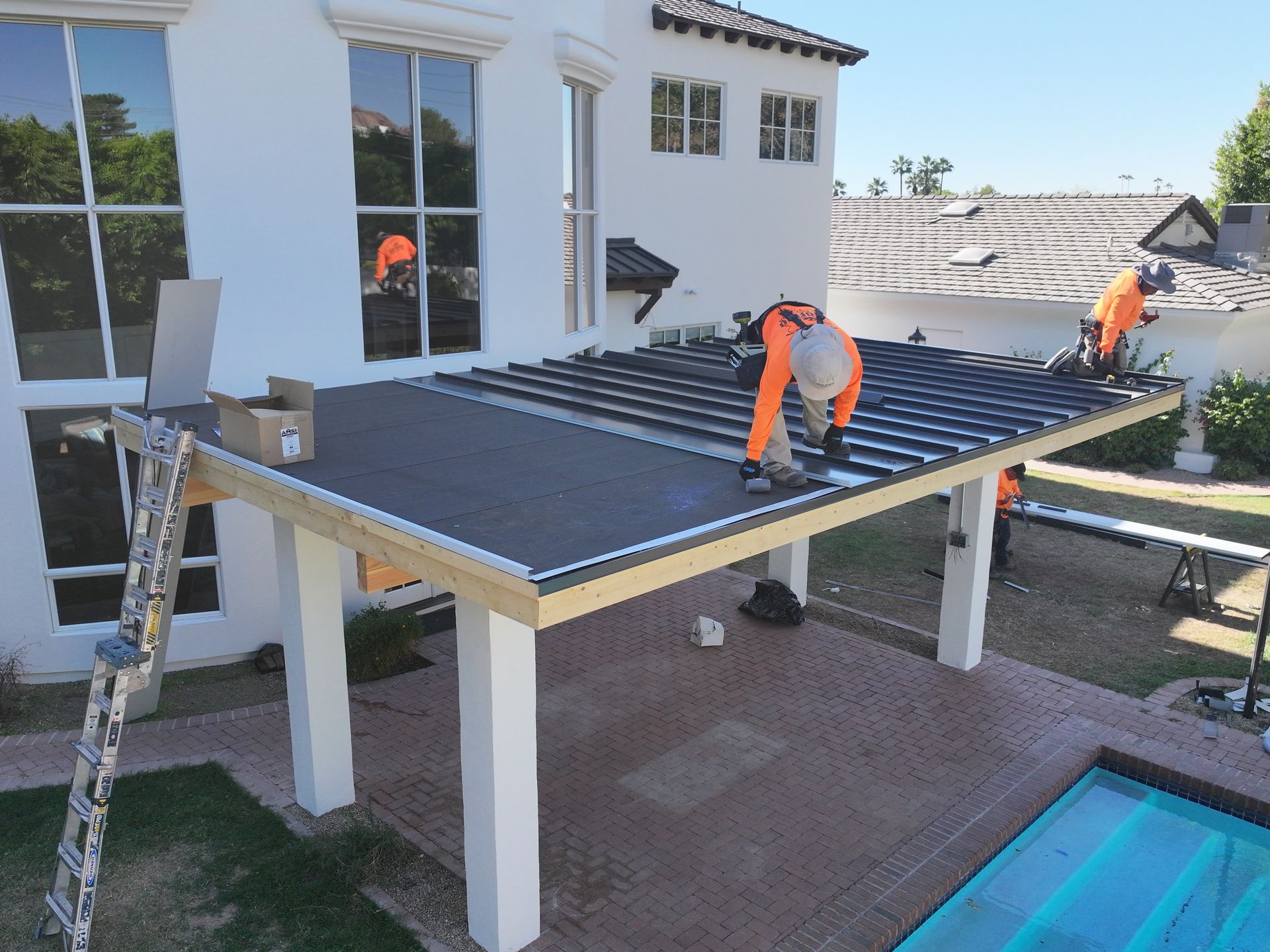 a group of men are working on a roof next to a pool