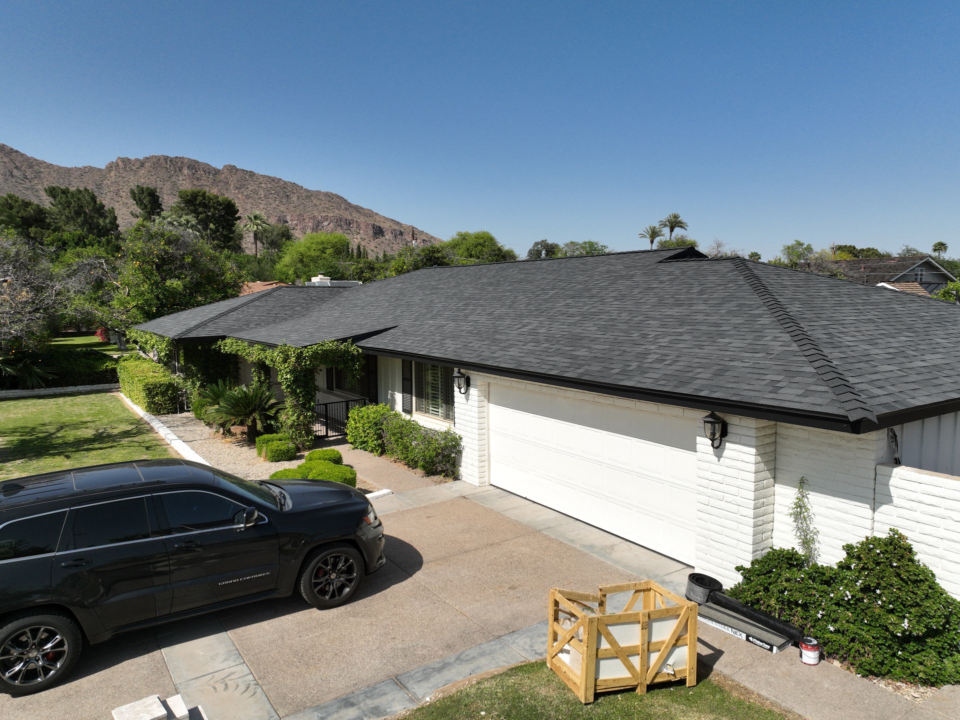 a black car is parked in front of a house with mountains in the background