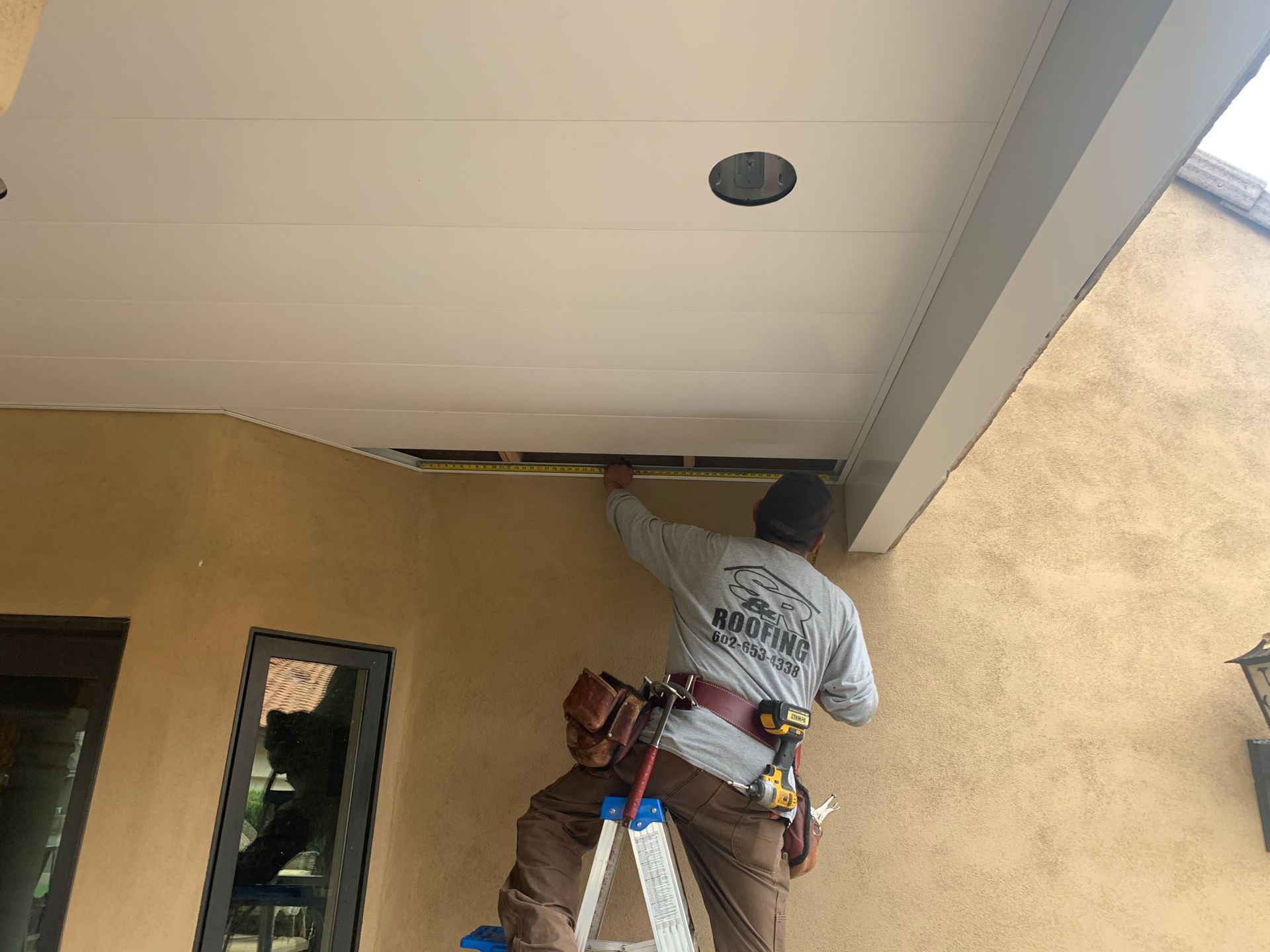 a man is standing on a ladder working on the ceiling of a building