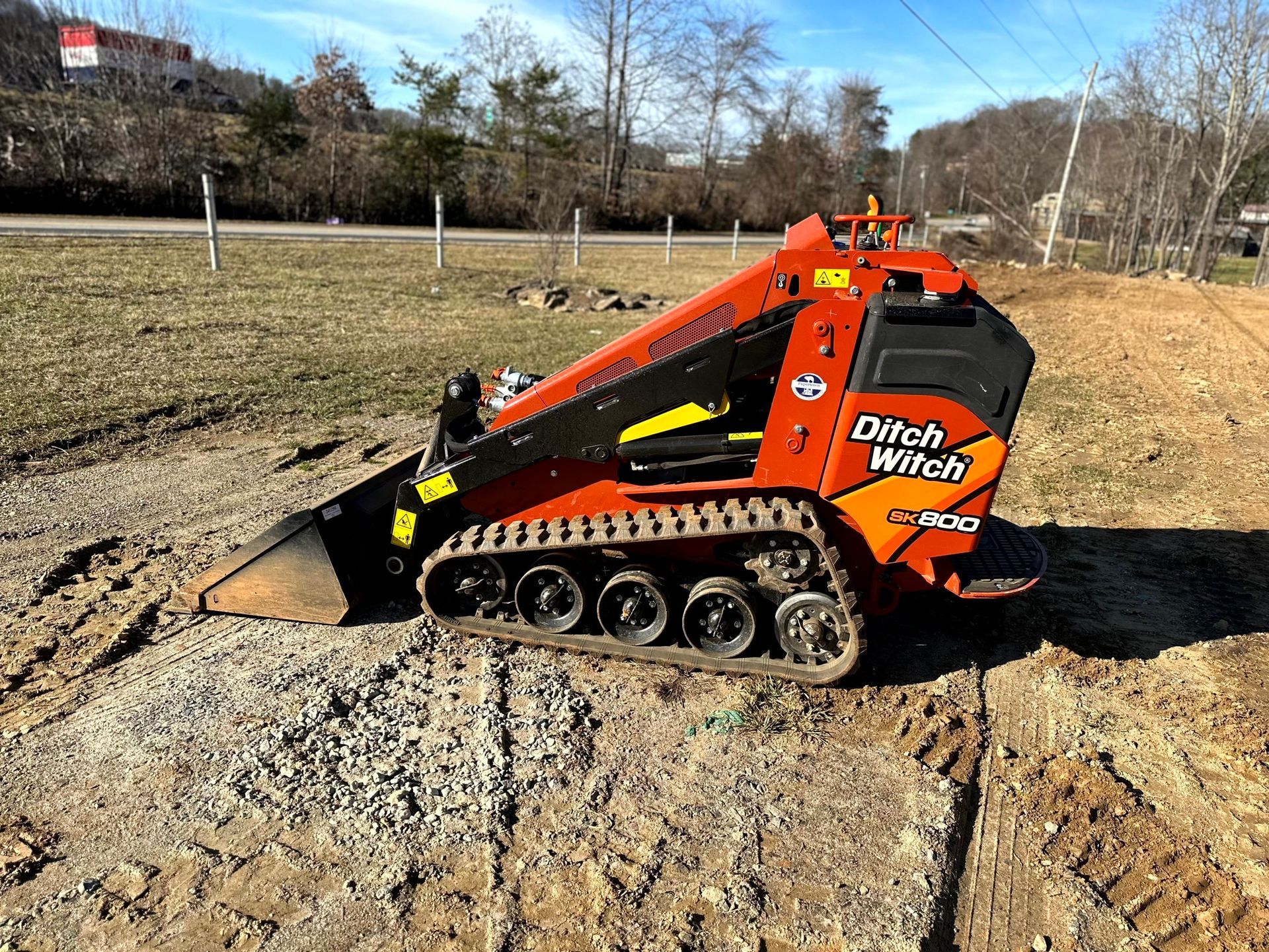 Orange and black Ditch Witch SK752 mini track loader on dirt and gravel.