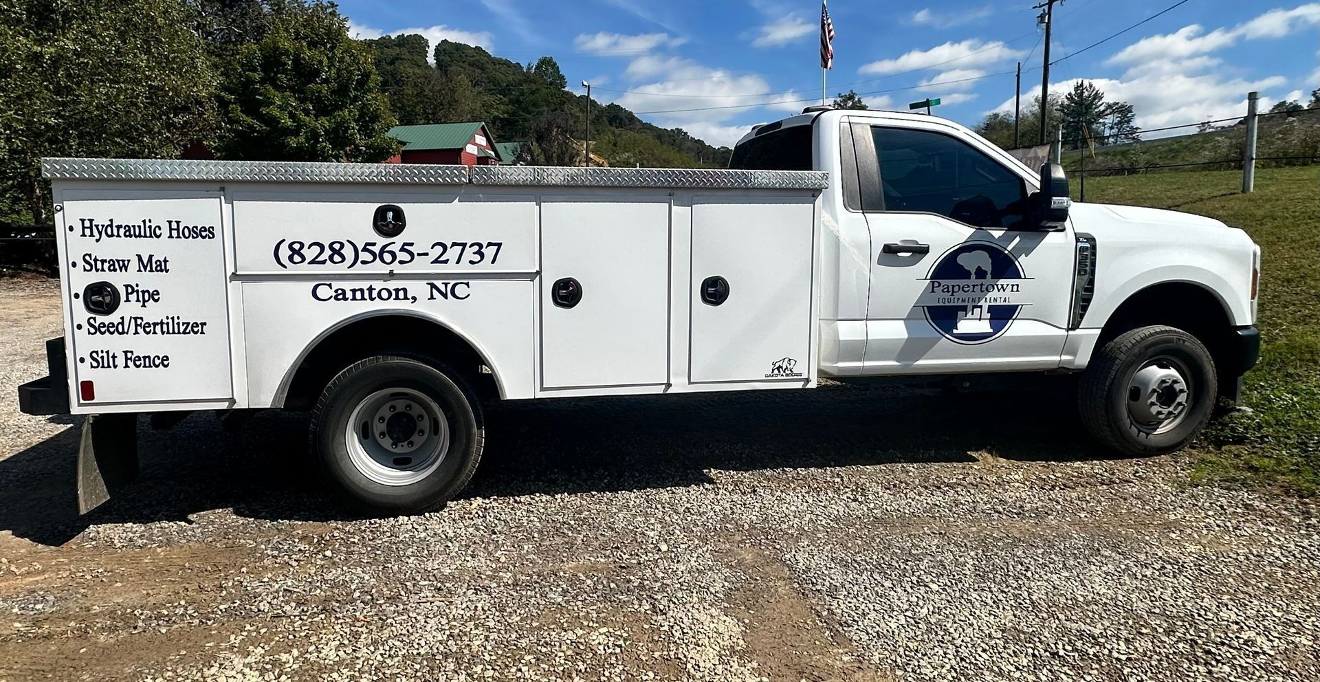 White service truck with logo and phone number, parked outdoors in a rural setting.