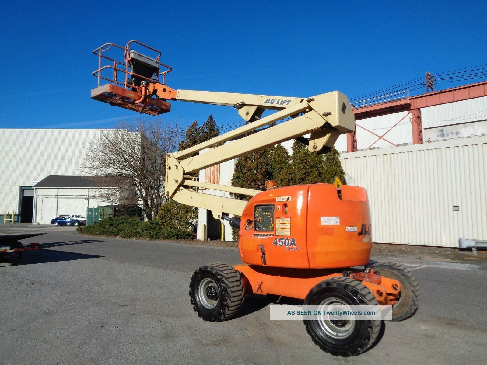 Orange and beige JLG articulating boom lift on an asphalt surface, outdoors.