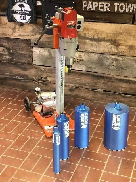 Core drilling machine with four blue core bits on a tiled floor.