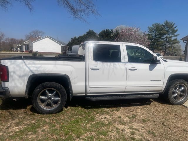 White pickup truck parked on grass, houses in background, sunny day.