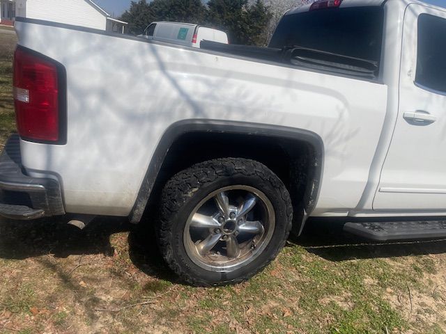 White pickup truck parked on grass, side view. The tire has a dirty tire.