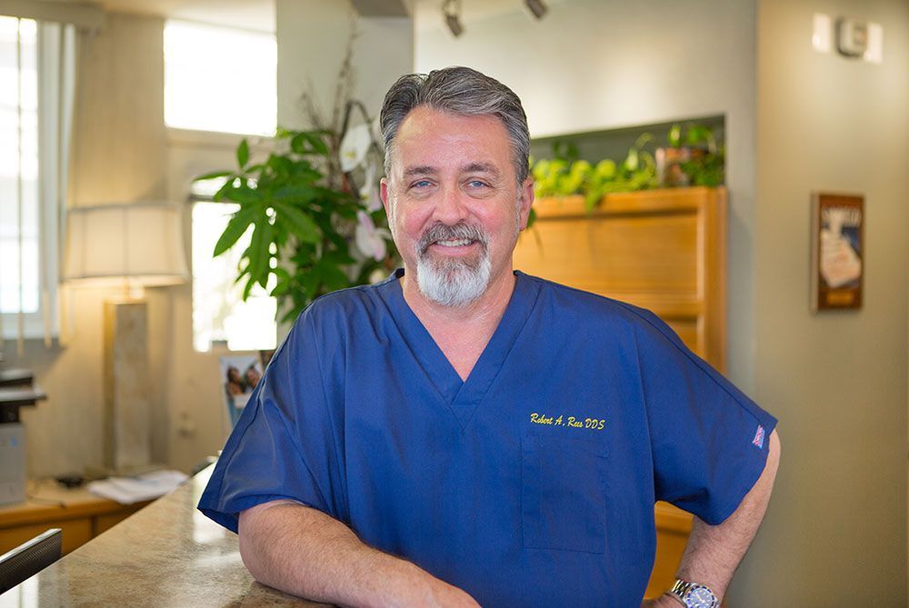 Smiling man in blue scrubs standing in a bright clinic lobby