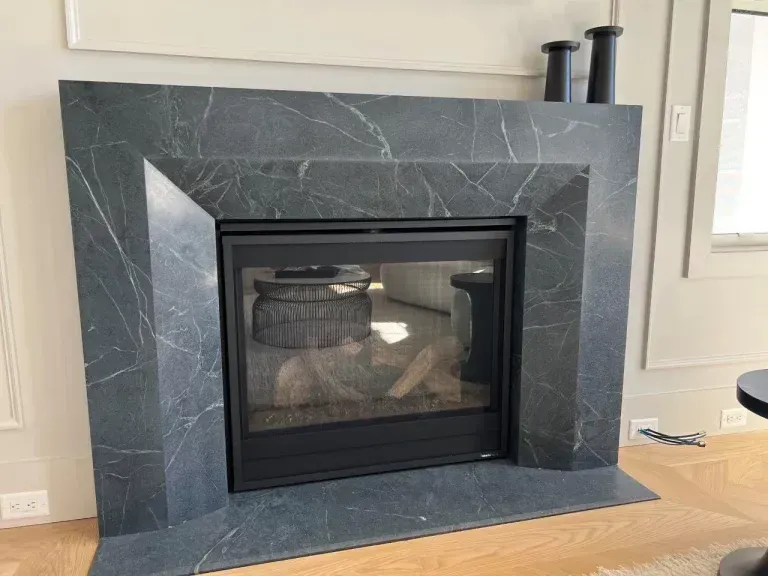 Dark gray tiled fireplace with black glass insert in a bright living room