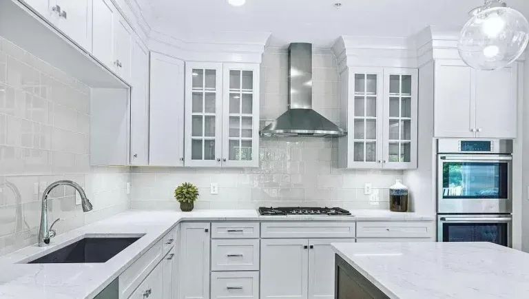 Bright white modern kitchen with stainless steel appliances and glass-front cabinets