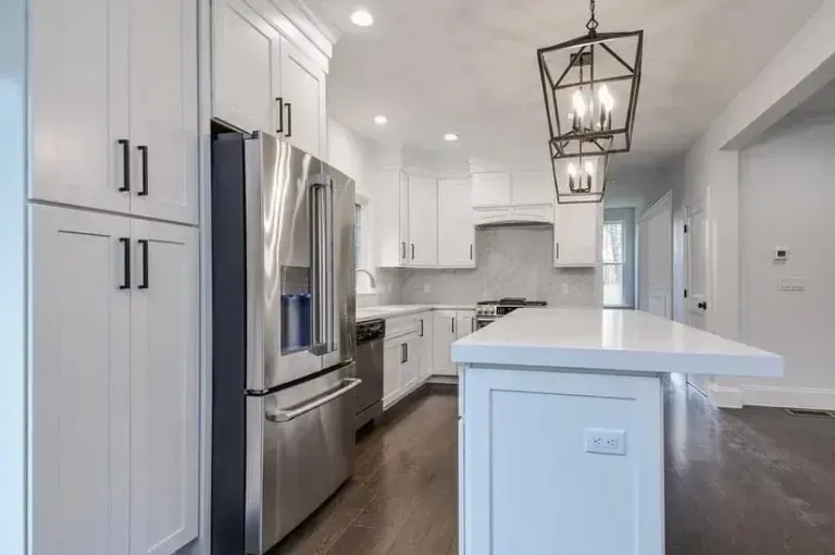 Bright white modern kitchen with stainless steel appliances, island, and pendant lights