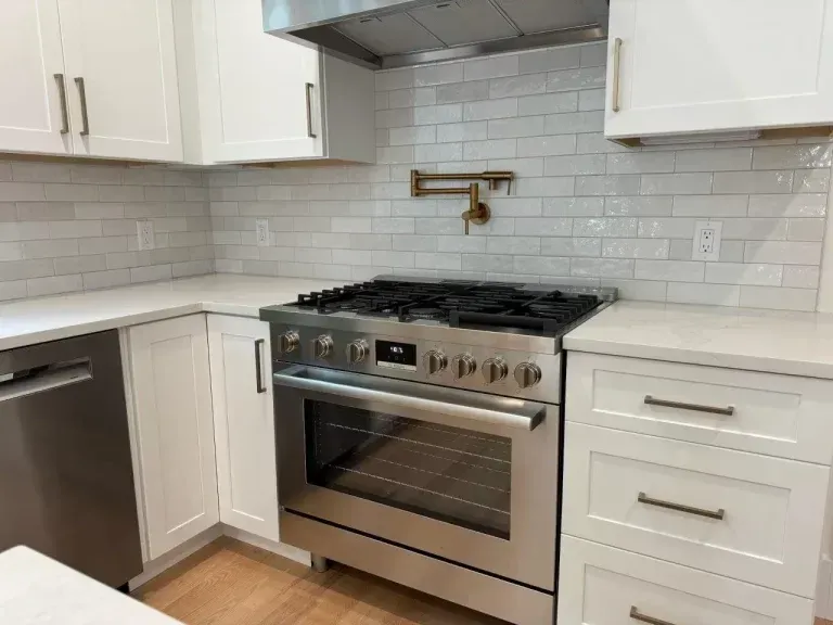 Modern kitchen with stainless steel stove, white cabinets, and light gray subway tile backsplash