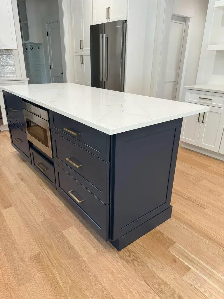 Dark navy kitchen island with white countertop in a bright modern kitchen