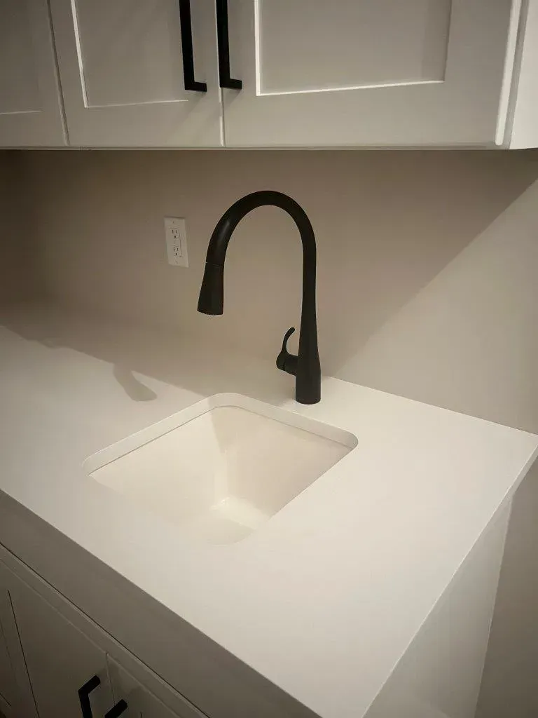 Modern white kitchen countertop with an under-mount sink and matte black faucet