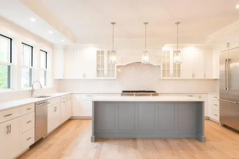 Bright modern kitchen with white cabinets, large island, and light wood floors