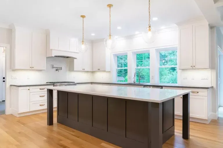 Bright modern kitchen with white cabinets, wood floors, and a large dark island countertop
