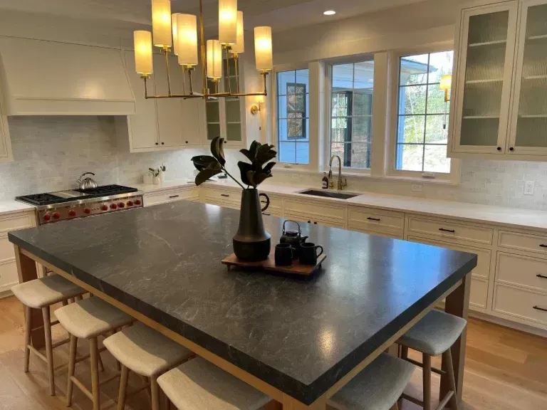 Modern kitchen with a large island, pendant lights, white cabinets, and a bright window nook