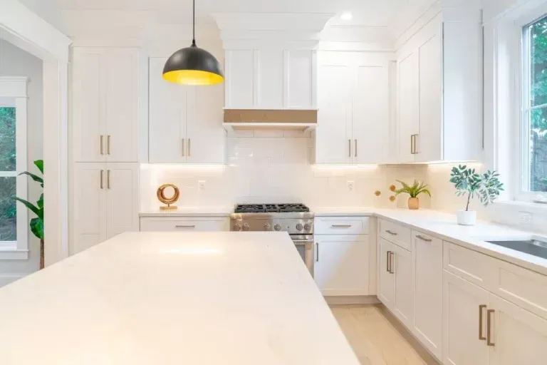 Bright white modern kitchen with island, pendant light, and stainless steel range
