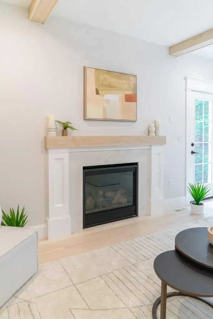 Bright living room with white fireplace, abstract art, plants, and a round coffee table