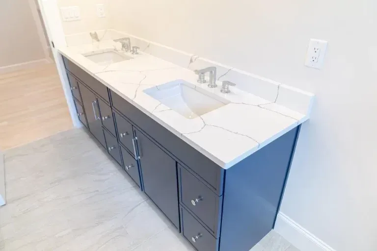 Modern bathroom vanity with white countertop, sink, faucet, and dark blue cabinets along a wall