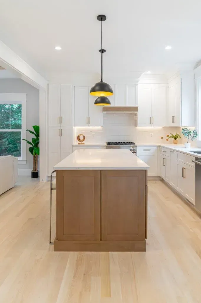 Bright modern kitchen with white cabinets, wood island, and pendant lights