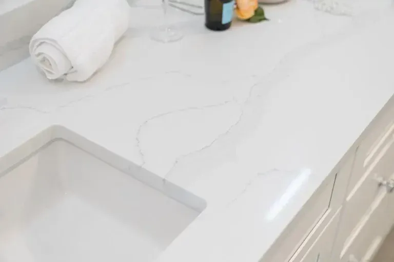 White kitchen countertop with built-in sink, rolled towel, and small decor items