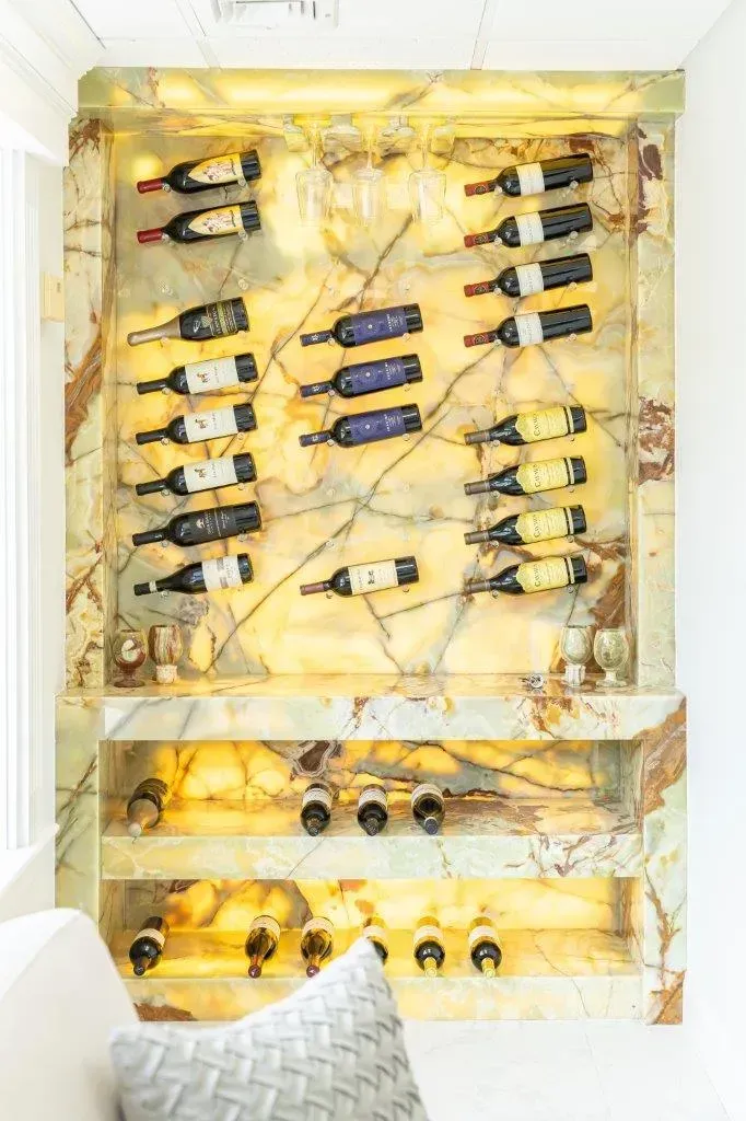 Wall-mounted yellow wine rack with several bottles displayed horizontally above a sofa.