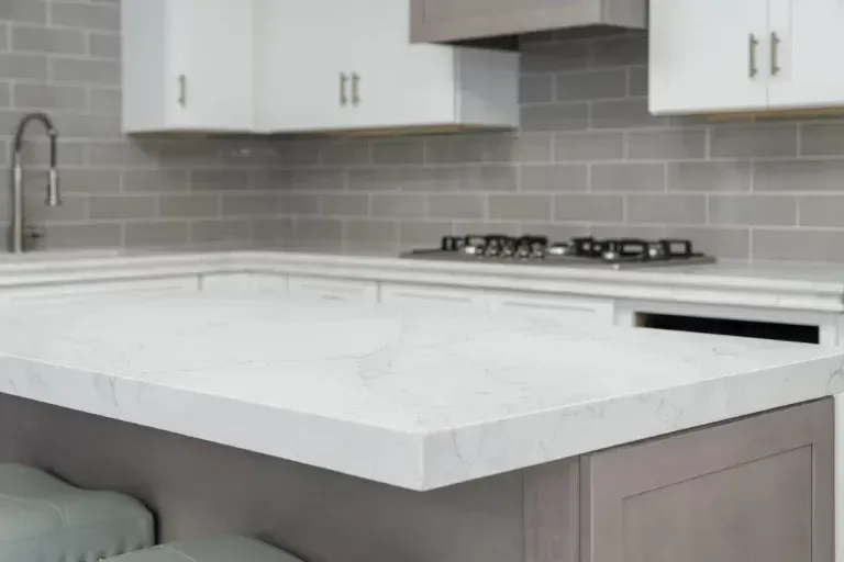 Modern kitchen with white island, gray cabinets, subway tile backsplash, and gas cooktop