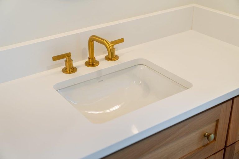 White bathroom vanity with integrated sink and gold faucet hardware