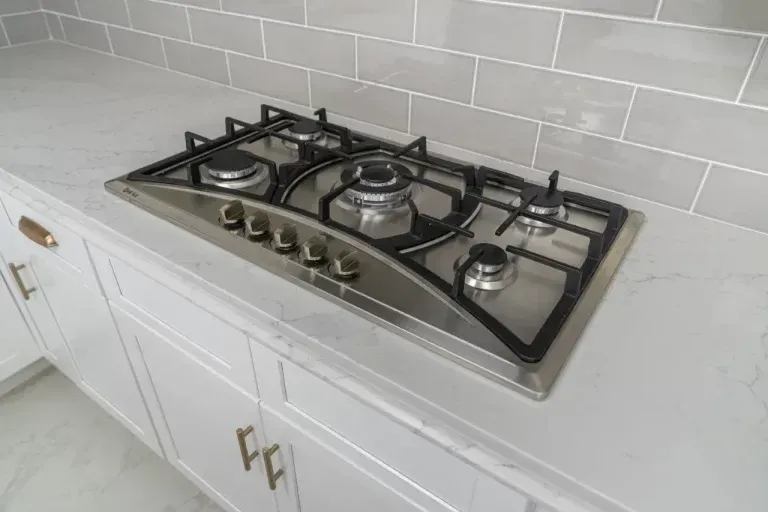 Stainless steel gas cooktop with four burners on a white kitchen countertop