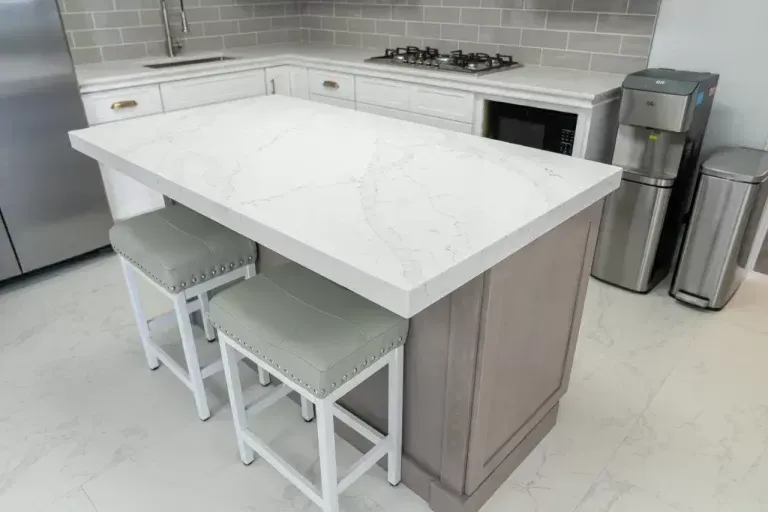 Modern kitchen island with white countertop, two stools, and stainless appliances