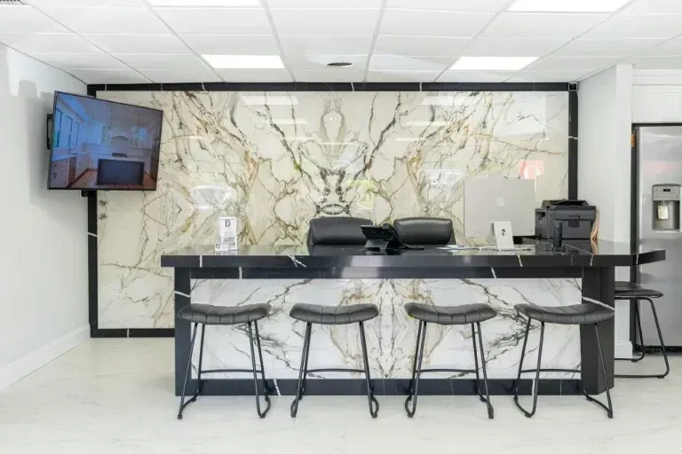 Modern lobby with marble wall, black counter, stools, and wall-mounted TV