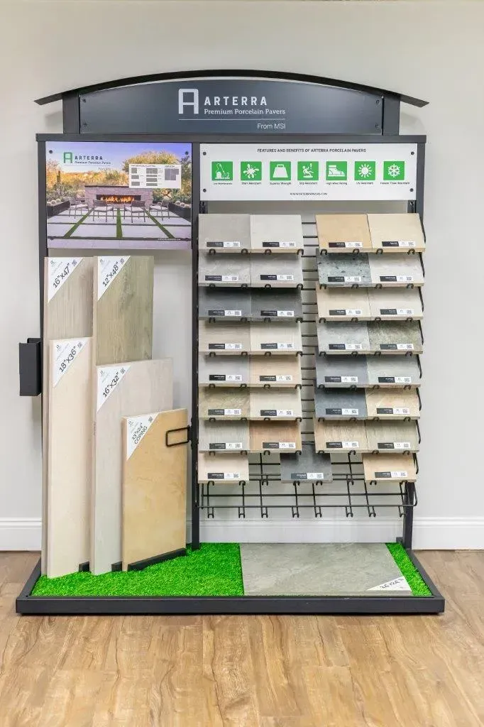 Display of building materials samples in a showroom, with tiles, panels, and shelving in a black stand