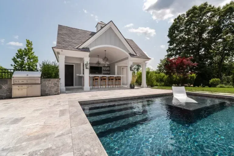 Modern house with a covered patio beside a blue swimming pool and lounge chair