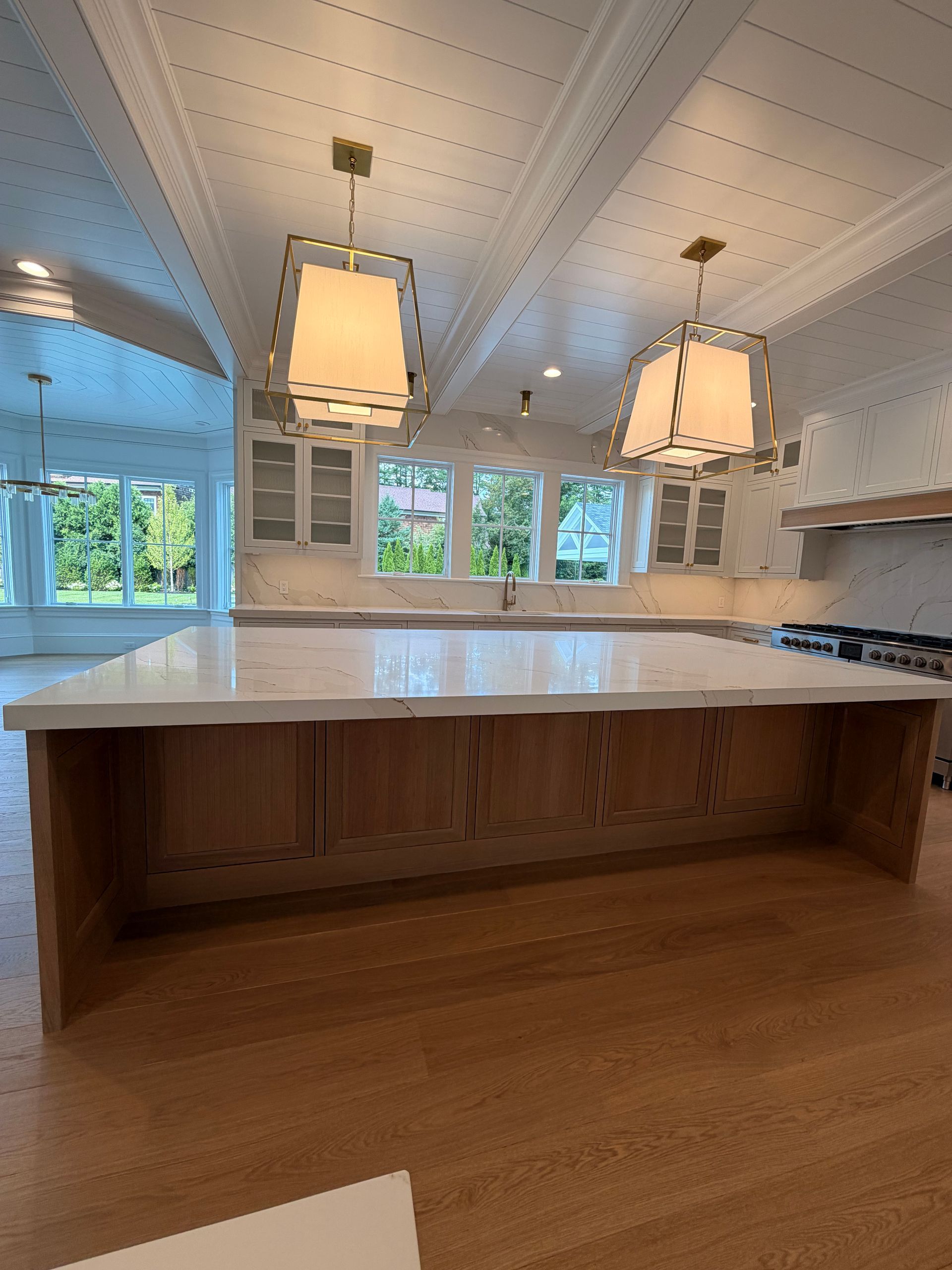 Bright kitchen with a large island, white cabinetry, and hanging pendant lights beneath a vaulted ceiling