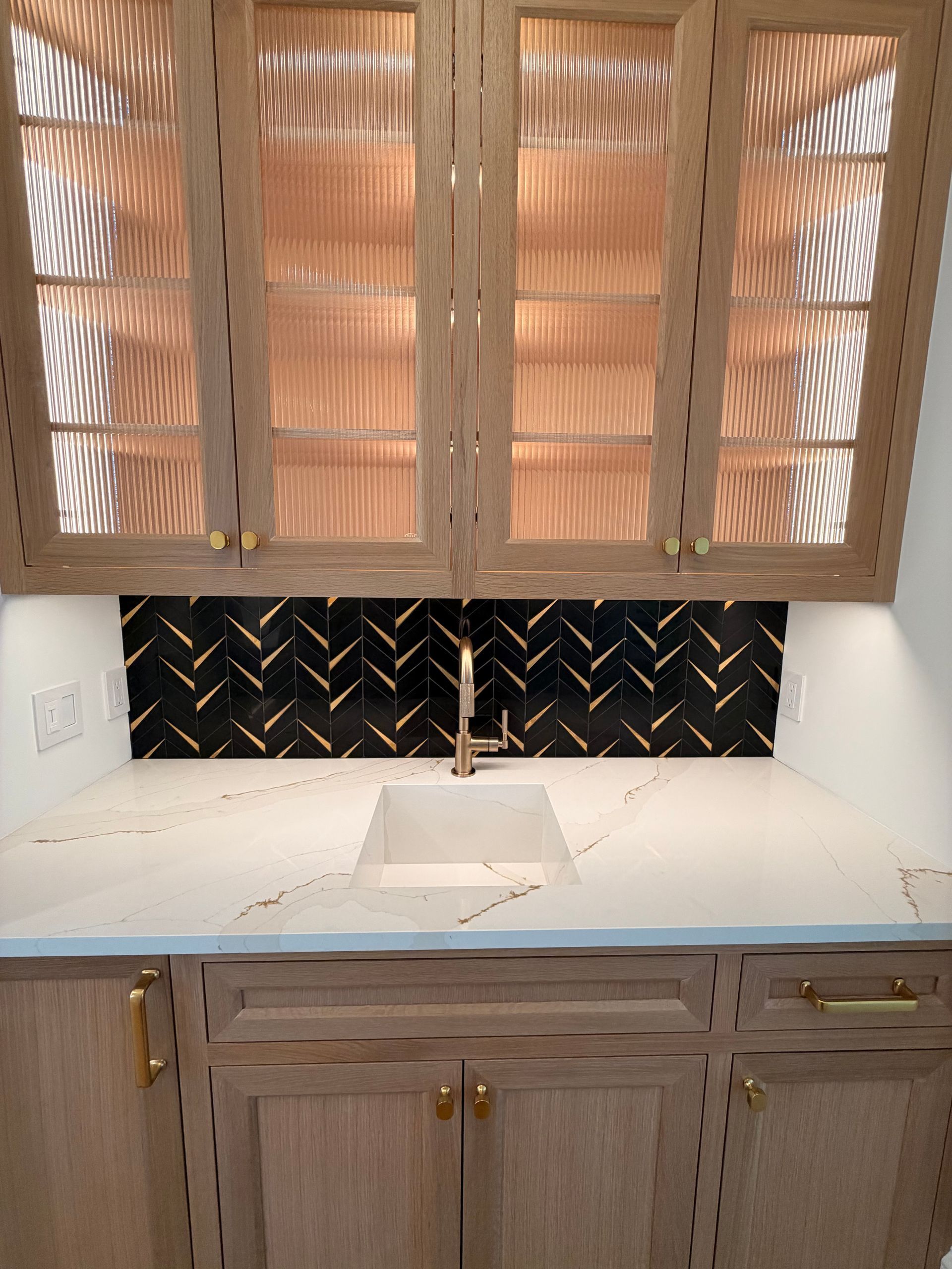Kitchen cabinets and countertop with torn backsplash and damaged, unfinished wall area