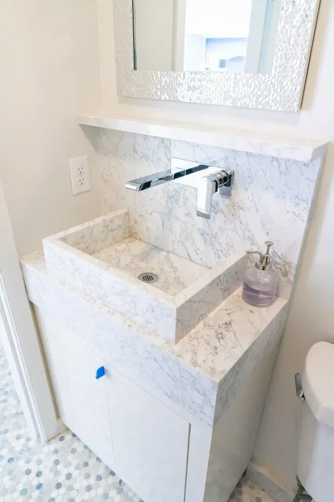 Modern bathroom sink vanity with marble countertop, chrome faucet, mirror, and soap dispenser