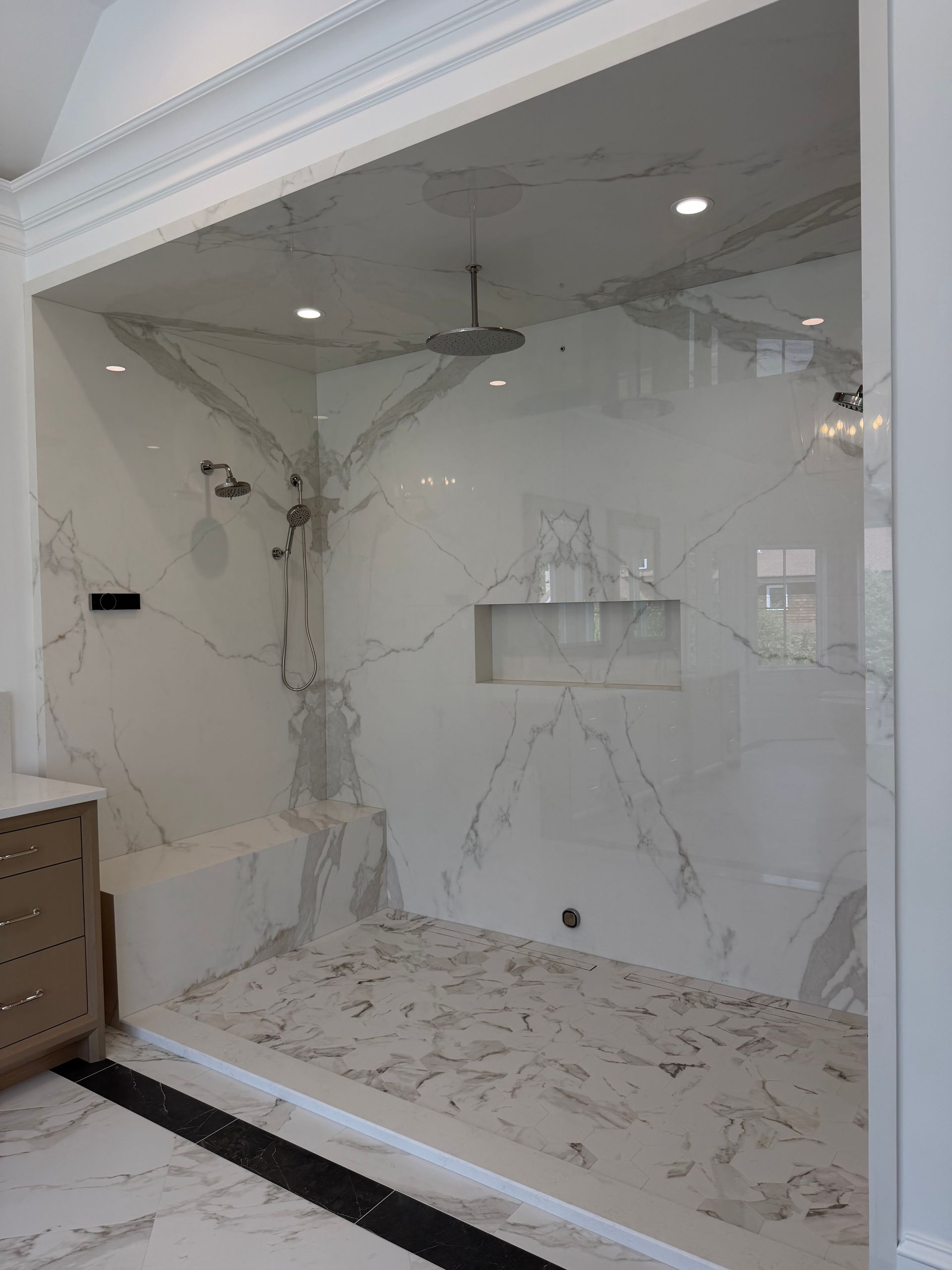 White marble-style interior display niche with a ceiling fan, recessed lights, and a brown cabinet at left.