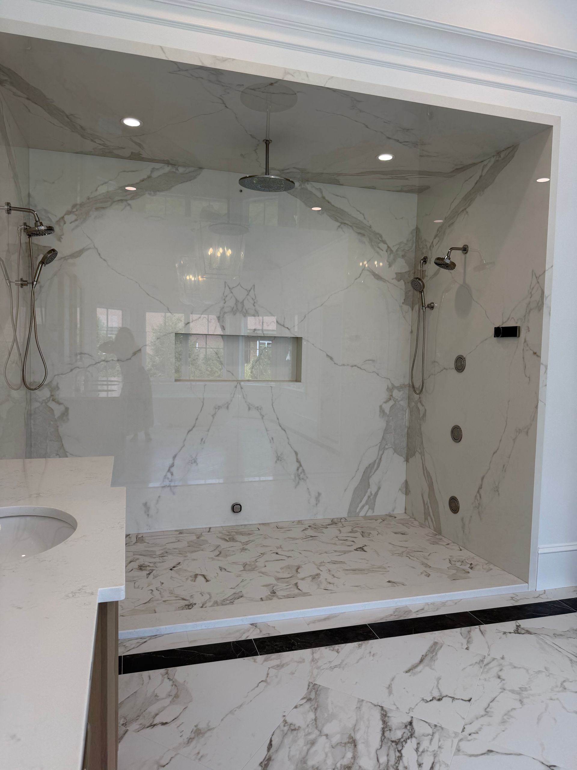 Luxury marble bathroom with walk-in shower, bench, and recessed ceiling lights