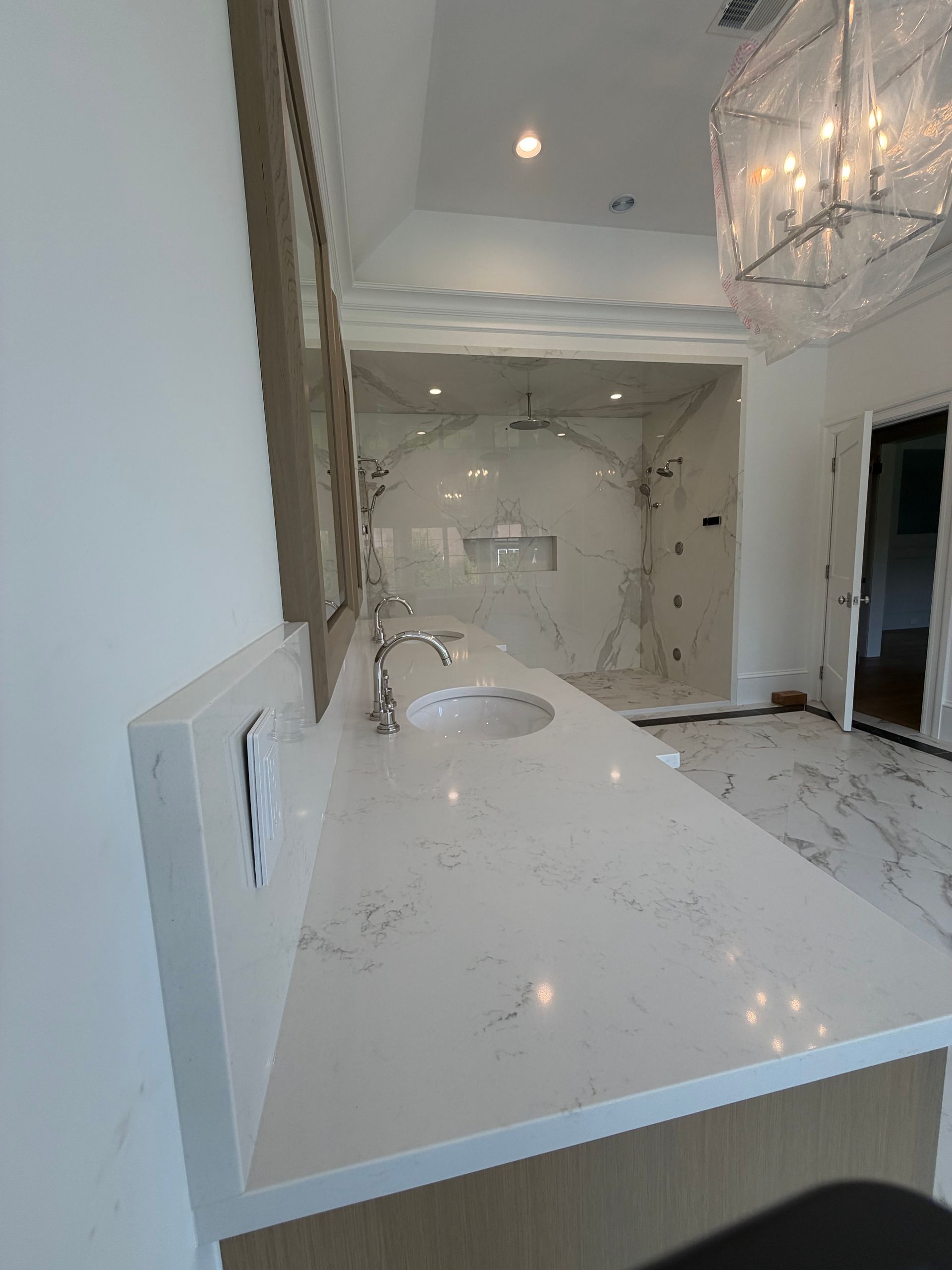 Bright white marble bathroom vanity with sink, mirror, and crystal chandelier in a luxurious interior