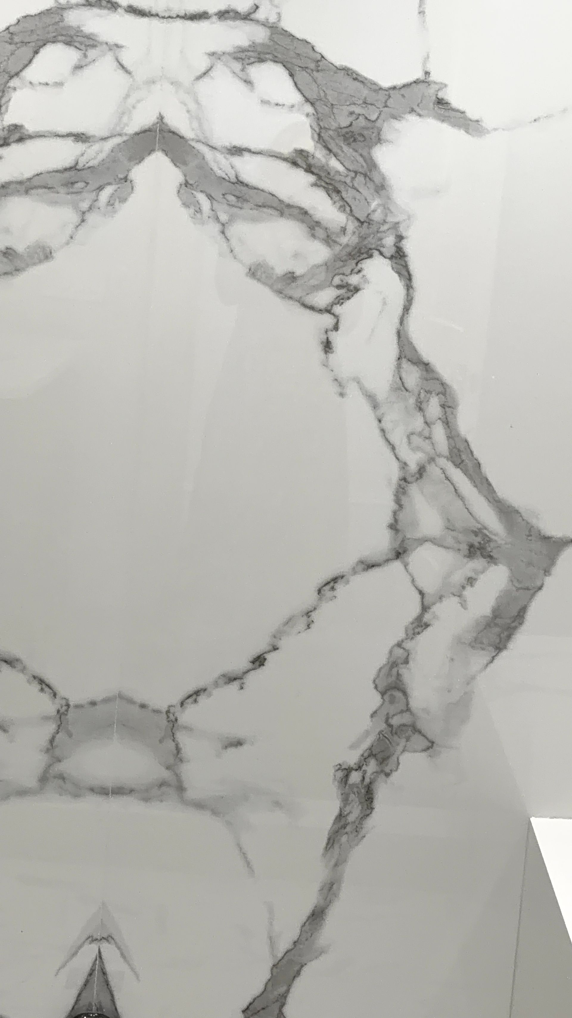White and gray marble-patterned surface with dark veining and a small triangular mark near the bottom.