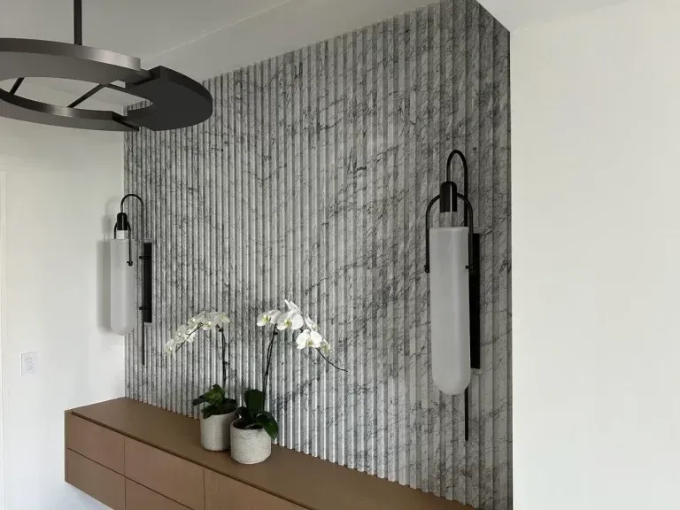 Modern interior with vertical tile accent wall, pendant lights, and a wooden console with white orchids.